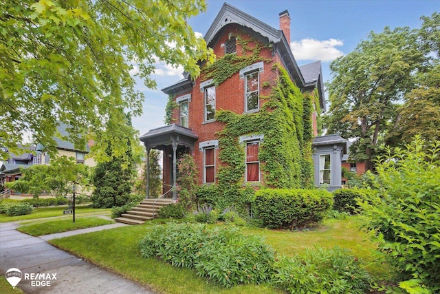616 S Warren Ave, Saginaw, MI 48607 - view of front of house with a chimney, a front yard, and brick siding