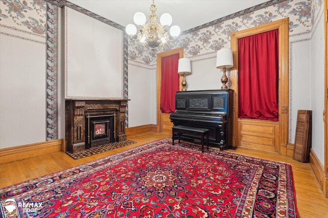616 S Warren Ave, Saginaw, MI 48607 - living area featuring wallpapered walls, wood finished floors, a chandelier, and a fireplace with flush hearth