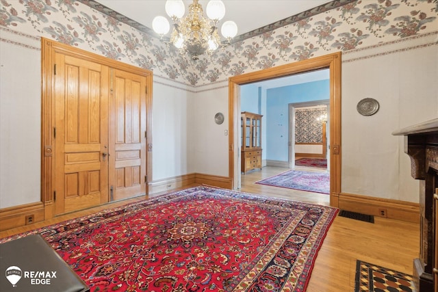 616 S Warren Ave, Saginaw, MI 48607 - entrance foyer featuring wallpapered walls, a chandelier, and wood finished floors
