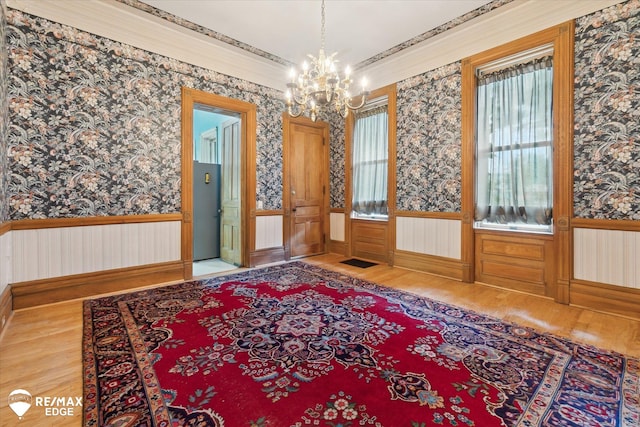 616 S Warren Ave, Saginaw, MI 48607 - spare room with wallpapered walls, a wainscoted wall, wood finished floors, and a chandelier