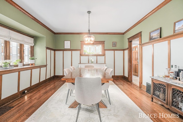 1035 Fountain St NE, Grand Rapids, MI 49503 - dining room featuring wood finished floors, a chandelier, healthy amount of natural light, and crown molding