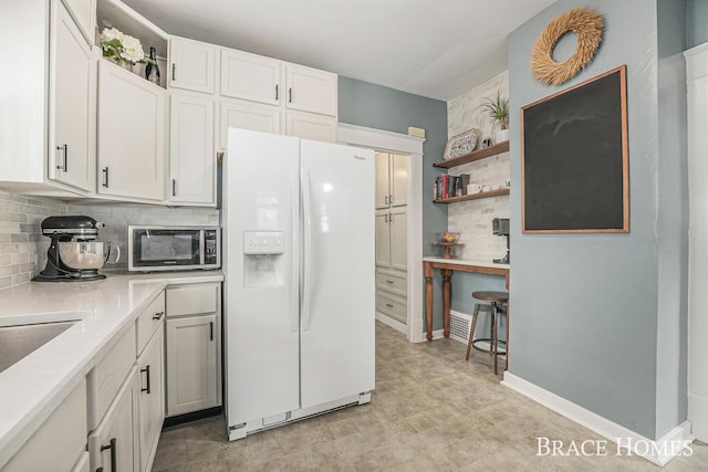 1035 Fountain St NE, Grand Rapids, MI 49503 - kitchen featuring white fridge with ice dispenser, stainless steel microwave, decorative backsplash, light countertops, and open shelves