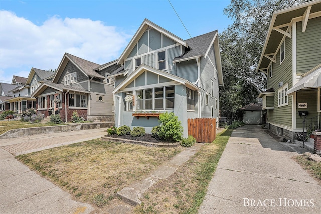 1035 Fountain St NE, Grand Rapids, MI 49503 - view of front of house featuring concrete driveway, a sunroom, a residential view, an outbuilding, and roof with shingles