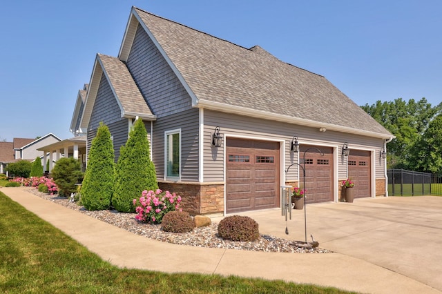 12529 E Tuscola Rd, Frankenmuth, MI 48734 - view of property exterior with concrete driveway, roof with shingles, stone siding, and a garage