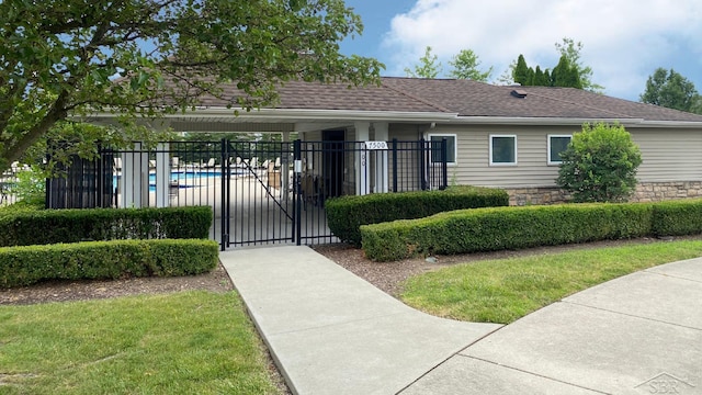 3244 Pine Run Dr, Swartz Creek, MI 48473 - view of front of property with a community pool, a shingled roof, a gate, and stone siding