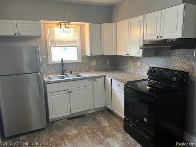 1147 Norton St, Flint, MI 48529 - kitchen featuring freestanding refrigerator, black electric range oven, under cabinet range hood, and white cabinetry