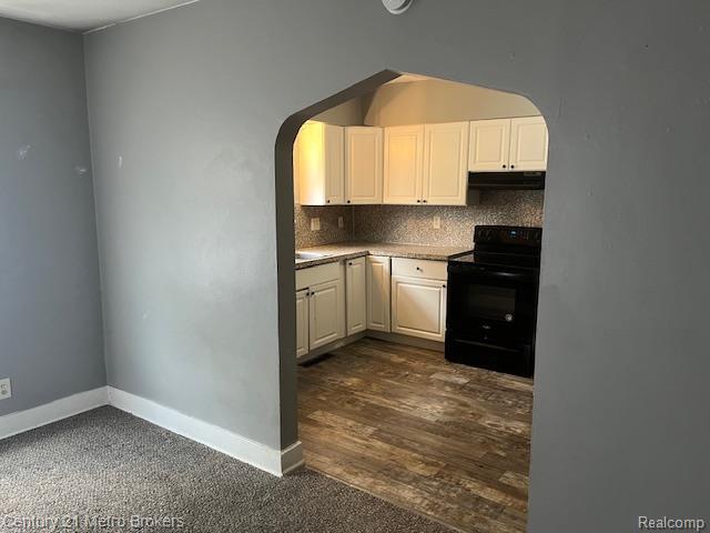 1147 Norton St, Flint, MI 48529 - kitchen with black electric range, arched walkways, under cabinet range hood, and decorative backsplash