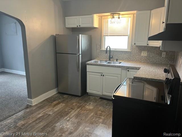 1147 Norton St, Flint, MI 48529 - kitchen with freestanding refrigerator, under cabinet range hood, white cabinetry, backsplash, and dark wood-type flooring