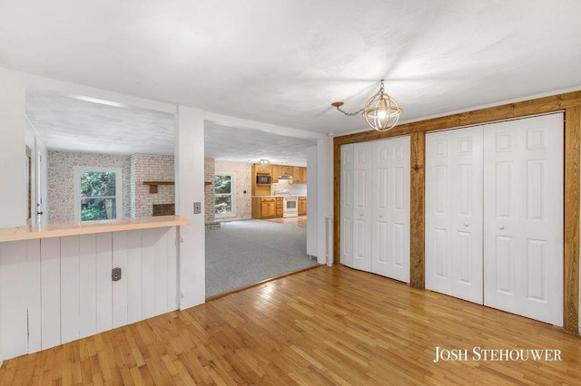 678 Pierce Rd, Plainwell, MI 49080 - unfurnished living room featuring wood finished floors and a chandelier