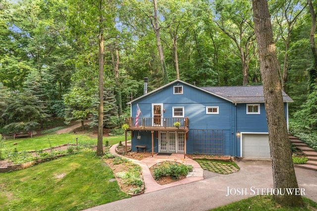 678 Pierce Rd, Plainwell, MI 49080 - view of front facade featuring driveway, a wooden deck, a front yard, an attached garage, and a view of trees