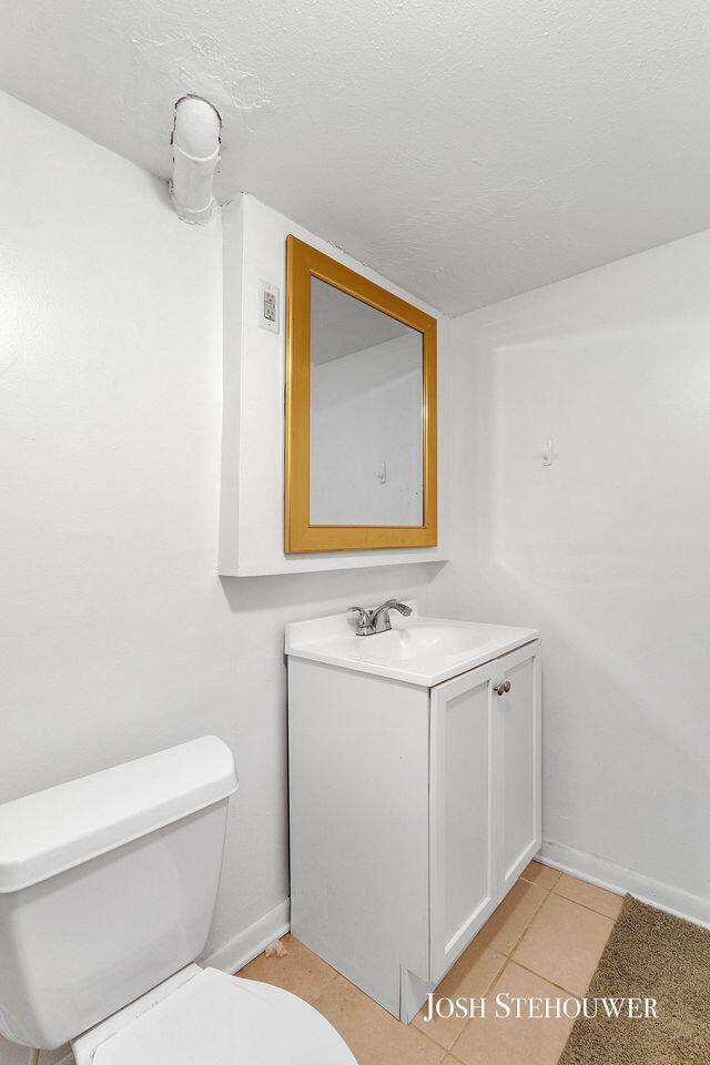 678 Pierce Rd, Plainwell, MI 49080 - half bath with vanity, tile patterned floors, and a textured ceiling