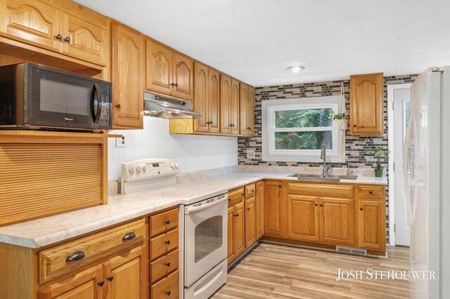 678 Pierce Rd, Plainwell, MI 49080 - kitchen with electric range, black microwave, under cabinet range hood, decorative backsplash, and light wood-type flooring