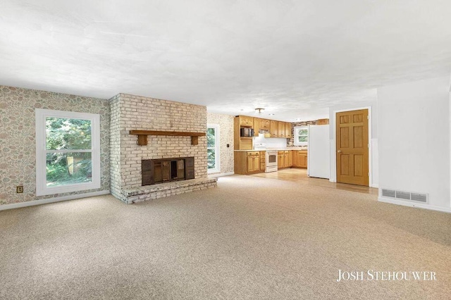 678 Pierce Rd, Plainwell, MI 49080 - unfurnished living room with wallpapered walls, a brick fireplace, and light carpet