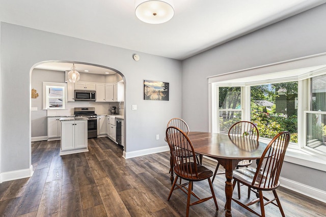 412 N Robert St, Ludington, MI 49431 - dining space featuring arched walkways and dark wood-style floors