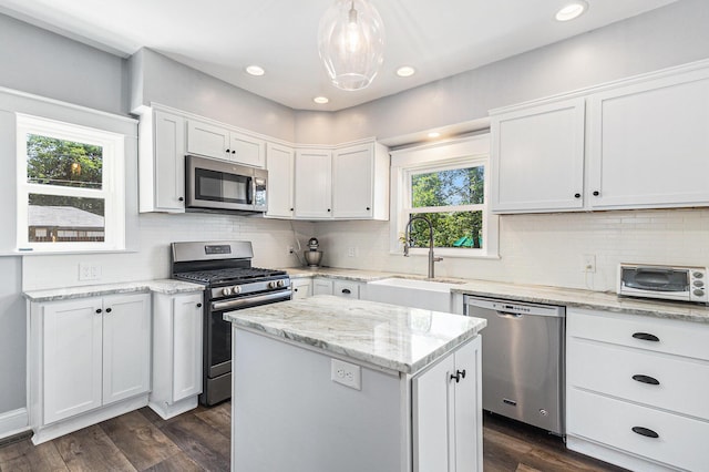 412 N Robert St, Ludington, MI 49431 - kitchen with stainless steel appliances, white cabinetry, decorative backsplash, a center island, and recessed lighting