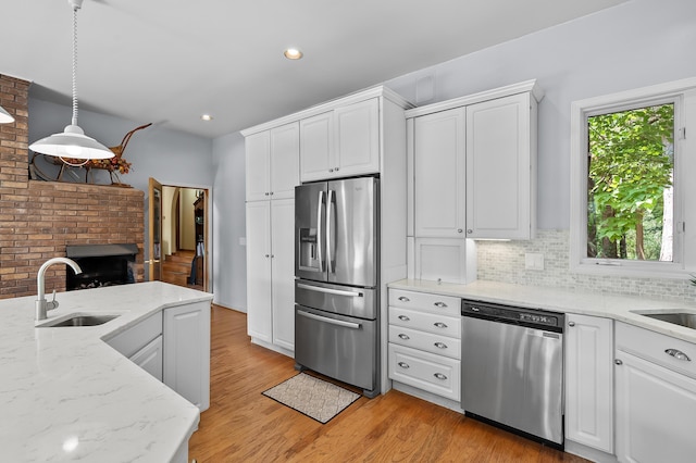 630 N 2nd St, Kalamazoo, MI 49009 - kitchen featuring appliances with stainless steel finishes, light wood-style flooring, white cabinets, backsplash, and hanging light fixtures