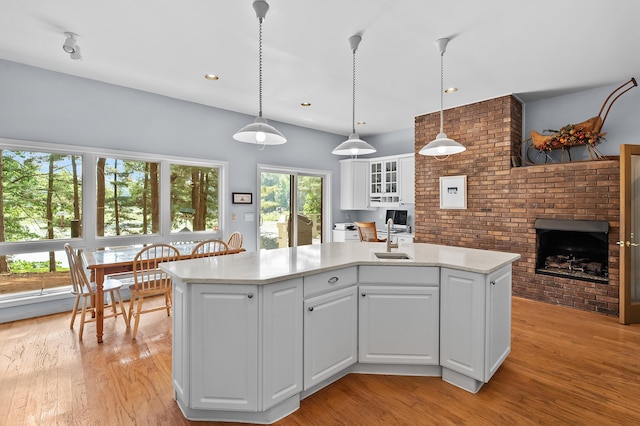 630 N 2nd St, Kalamazoo, MI 49009 - kitchen with a brick fireplace, light countertops, white cabinetry, light wood-type flooring, and decorative light fixtures