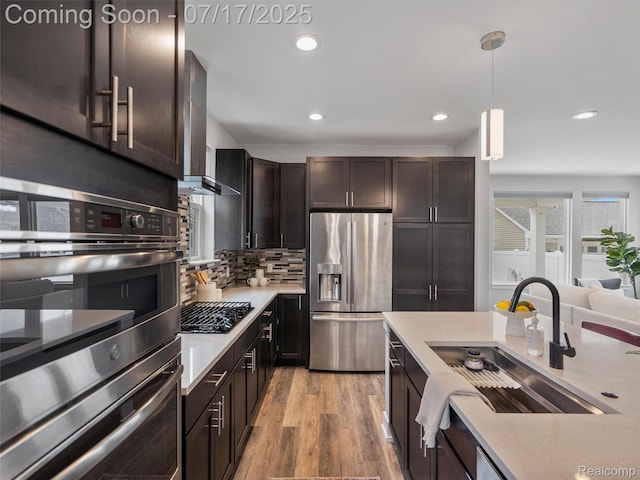 482 Wilson St, Ferndale, MI 48220 - kitchen featuring stainless steel appliances, light countertops, dark brown cabinetry, tasteful backsplash, and wall chimney range hood