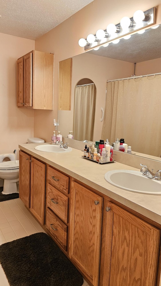 157 Carson Dr Unit 175, Westland, MI 48185 - bathroom featuring double vanity, a textured ceiling, a shower with shower curtain, and tile patterned floors