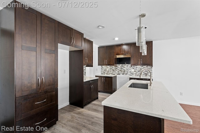 15679 Gulley St, Taylor, MI 48180 - kitchen with light wood-style flooring, decorative backsplash, dark brown cabinetry, light stone counters, and recessed lighting