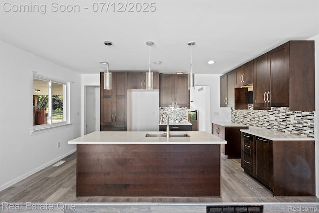 15679 Gulley St, Taylor, MI 48180 - kitchen with dark brown cabinetry, wood finished floors, decorative backsplash, a center island with sink, and recessed lighting