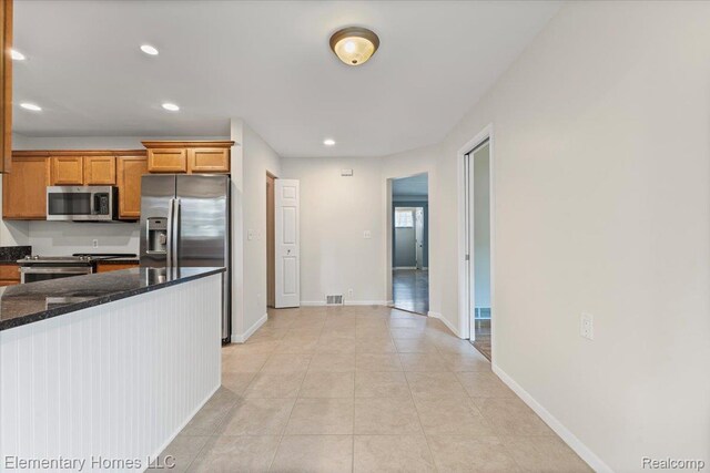 21142 Michael Ct, Saint Clair Shores, MI 48081 - kitchen with appliances with stainless steel finishes, light tile patterned flooring, recessed lighting, brown cabinetry, and dark stone counters