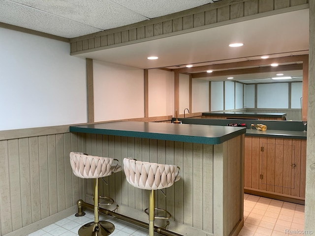 29494 Sylvan Ln Unit 6, Farmington Hills, MI 48334 - kitchen with dark countertops, a breakfast bar, light tile patterned floors, recessed lighting, and wainscoting
