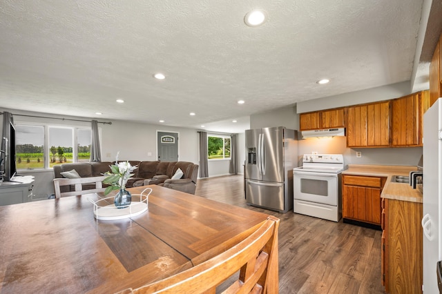 28644 Elm St, Dowagiac, MI 49047 - kitchen featuring white electric range, stainless steel fridge, under cabinet range hood, brown cabinets, and recessed lighting