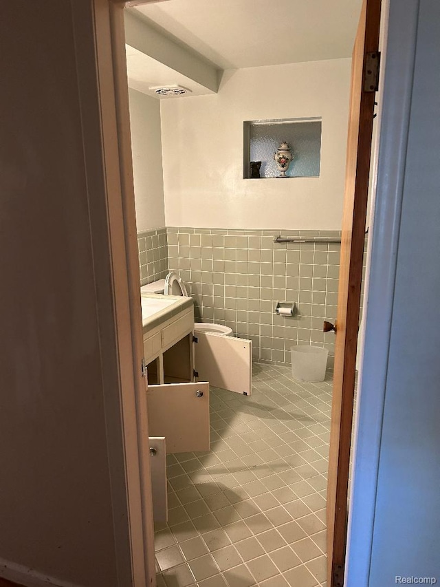 4230 Wendell Rd, West Bloomfield, MI 48323 - half bath featuring vanity, tile walls, tile patterned floors, and a wainscoted wall