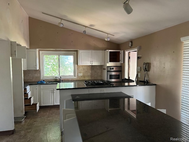 4230 Wendell Rd, West Bloomfield, MI 48323 - kitchen with lofted ceiling, rail lighting, dark countertops, oven, and tasteful backsplash