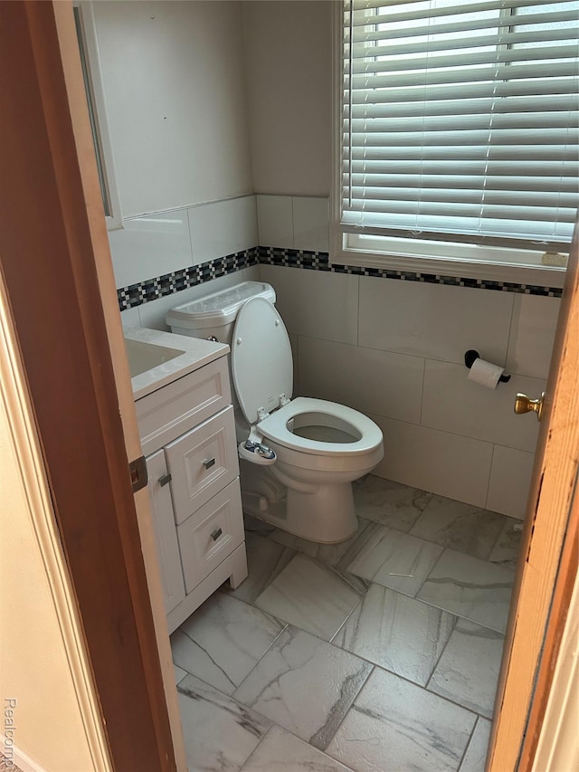 4230 Wendell Rd, West Bloomfield, MI 48323 - bathroom with marble look tile flooring, tile walls, vanity, and wainscoting