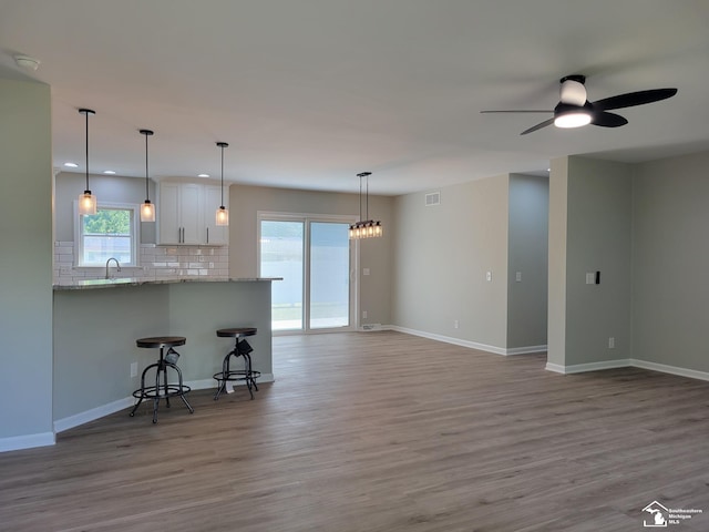 2844 1st St, Monroe, MI 48162 - kitchen with tasteful backsplash, ceiling fan, wood finished floors, a kitchen bar, and white cabinets