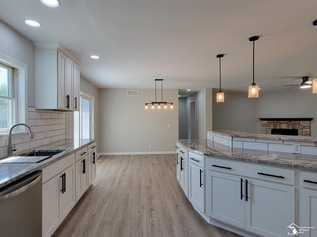 2844 1st St, Monroe, MI 48162 - kitchen featuring stainless steel dishwasher, decorative backsplash, ceiling fan, light wood finished floors, and white cabinetry