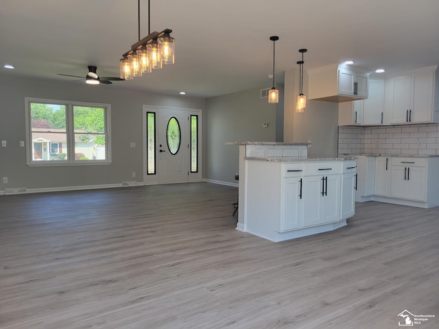 2844 1st St, Monroe, MI 48162 - kitchen featuring open floor plan, a ceiling fan, light wood-type flooring, tasteful backsplash, and hanging light fixtures