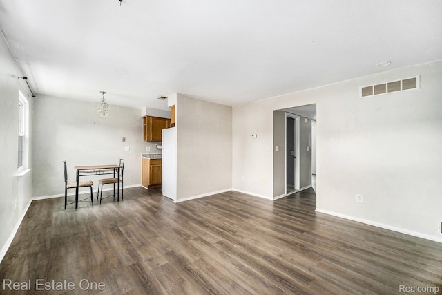 204 Princeton Dr, South Lyon, MI 48178 - unfurnished living room featuring dark wood-style floors and a chandelier