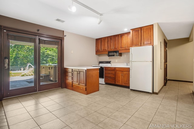 8608 Woodruff Dr SW, Byron Center, MI 49315 - kitchen featuring white appliances, brown cabinets, light countertops, light tile patterned floors, and a peninsula
