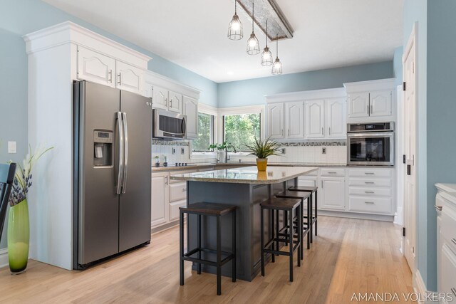 8608 Woodruff Dr SW, Byron Center, MI 49315 - kitchen featuring stainless steel appliances, white cabinets, backsplash, and a breakfast bar area