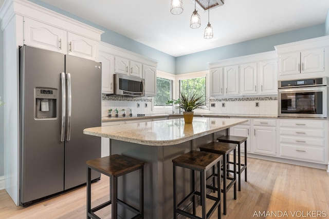 8608 Woodruff Dr SW, Byron Center, MI 49315 - kitchen featuring appliances with stainless steel finishes, white cabinetry, and a kitchen breakfast bar