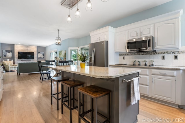 8608 Woodruff Dr SW, Byron Center, MI 49315 - kitchen with stainless steel appliances, white cabinets, a center island, light stone countertops, and a breakfast bar area