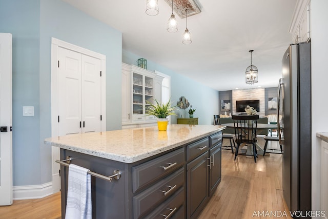 8608 Woodruff Dr SW, Byron Center, MI 49315 - kitchen with freestanding refrigerator, light wood-type flooring, a kitchen island, white cabinetry, and light stone counters