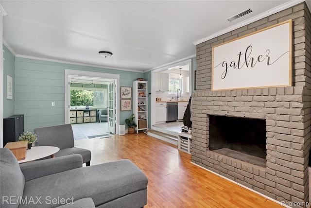 1406 Country View Ln, Flint, MI 48532 - living room featuring ornamental molding, light wood-style flooring, healthy amount of natural light, and a brick fireplace