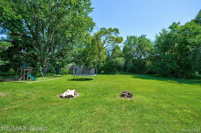 1406 Country View Ln, Flint, MI 48532 - view of green lawn featuring a trampoline, a playground, and an outdoor fire pit