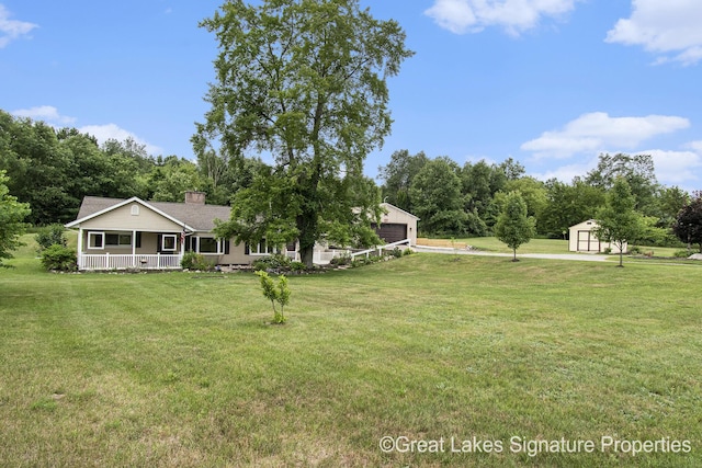 6047 Belding Rd, Belding, MI 48809 - view of green lawn featuring a porch, a garage, and a shed