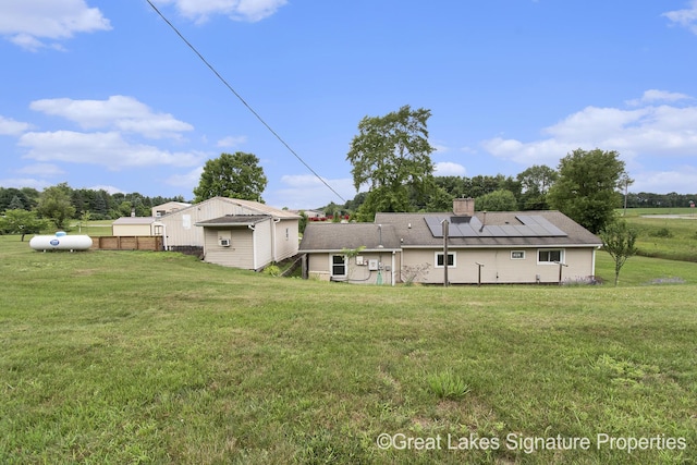 6047 Belding Rd, Belding, MI 48809 - back of house with solar panels, a yard, and a chimney