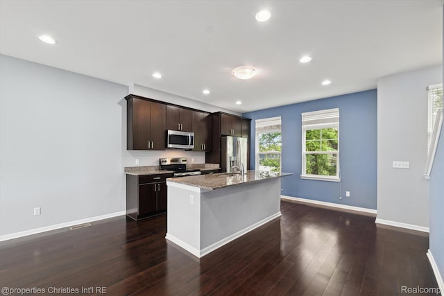 1051 N Sherman Dr Unit B19, Royal Oak, MI 48067 - kitchen with stainless steel appliances, a kitchen island with sink, dark brown cabinetry, dark wood-type flooring, and light stone countertops