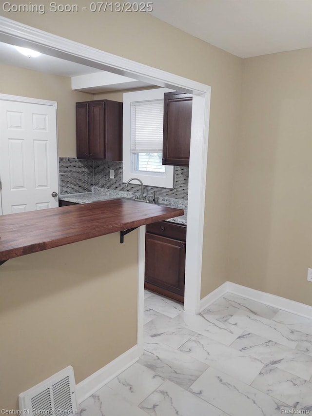 19928 Avon Ave, Detroit, MI 48219 - kitchen with wood counters, dark brown cabinetry, light marble finish flooring, and tasteful backsplash