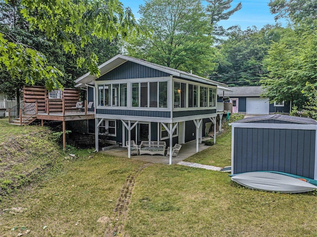 6706 E Carrigan Dr, Newaygo, MI 49337 - rear view of house featuring a sunroom, a wooden deck, a yard, a patio area, and a detached garage
