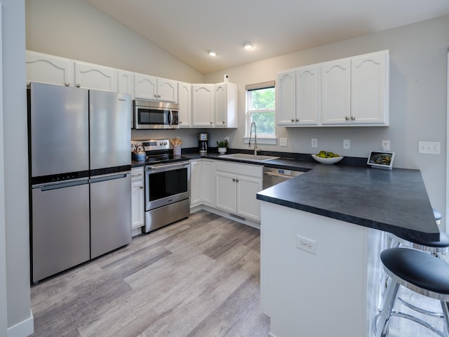 3740 Pristine Ave, Kalamazoo, MI 49048 - kitchen with stainless steel appliances, dark countertops, a peninsula, vaulted ceiling, and white cabinetry