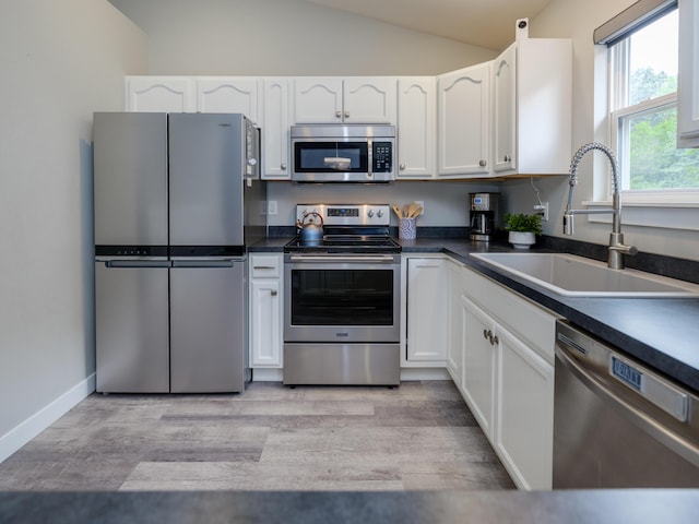 3740 Pristine Ave, Kalamazoo, MI 49048 - kitchen featuring appliances with stainless steel finishes, lofted ceiling, dark countertops, and white cabinetry