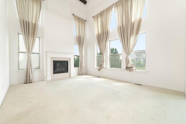 4215 Chandi Ct, Ypsilanti, MI 48197 - unfurnished living room with a towering ceiling, carpet flooring, and a glass covered fireplace